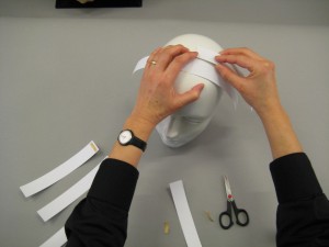Stripes of paper being placed on top of mannequin head
